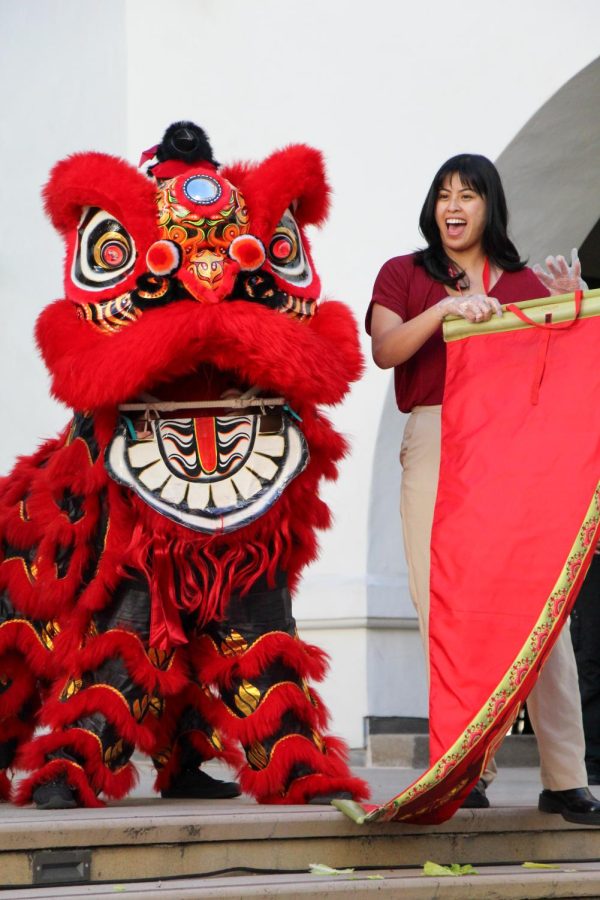 Angela Subido stands elated next to a dragon costume at the celebration. 